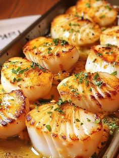 cooked scallops in a pan with herbs on top