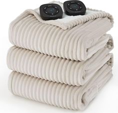 two speakers sitting on top of a pile of folded blankets with white sheets in the foreground