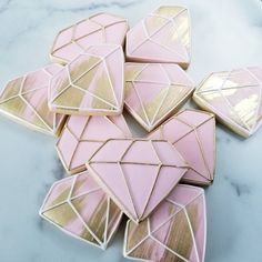 pink and gold decorated cookies sitting on top of a marble countertop next to each other