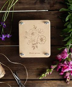 some flowers and scissors on a wooden table with wires, thread and paper clippings