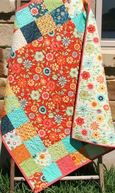 an orange and blue quilt sitting on top of a chair