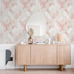 a dresser with a mirror on top of it next to a wallpapered wall