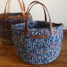 two baskets sitting on top of a wooden table covered in blue and multicolored fabric