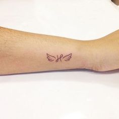 a person's arm with a small bird tattoo on the left side of their arm