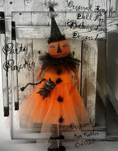 an orange and black halloween doll in a tutu skirt on a white wooden background