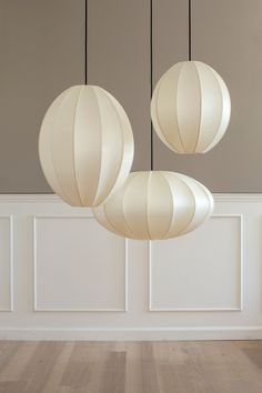 three lamps hanging from the ceiling in a room with wood flooring and white walls