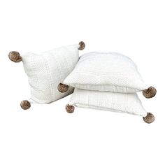 two white pillows with pom - poms on them