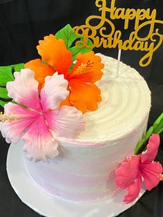 a white cake with flowers on top and a happy birthday sign