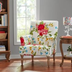 a chair with flowers on it in front of a book shelf and window sill