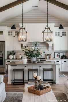 a living room and kitchen area in a house with white walls, wood floors and ceiling beams