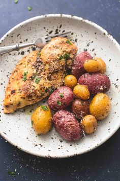 a white plate topped with chicken, potatoes and parmesan sprinkles