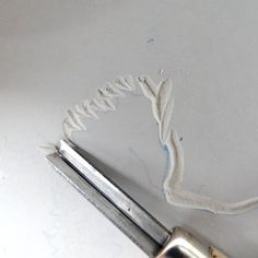 a close up of a pair of scissors on a table with white thread next to it