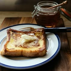 a piece of bread with butter on it sitting on a plate next to a jar of honey