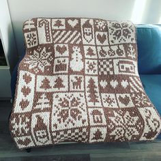 a brown and white knitted blanket sitting on top of a blue couch next to a window