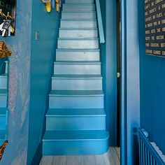 the stairs are painted bright blue and there is a teddy bear hanging on the wall