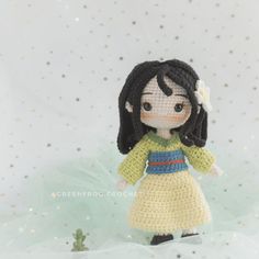 a crocheted doll is standing in the snow with her hand on her hip