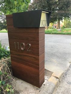 a mailbox sitting on the side of a road next to some bushes and trees