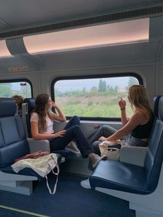 two women sitting in seats on a train looking out the window