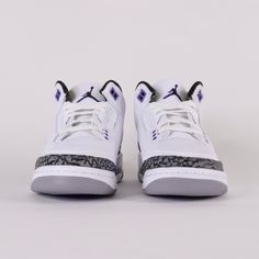 a pair of white sneakers with purple and black accents on the upper part of the shoe