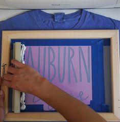 a person is holding a piece of paper with the word auburn on it in front of a frame