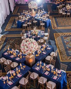 the tables are set up with blue linens and white flowers in centerpieces