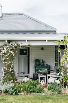 a white house with lots of greenery on the front porch and back door area