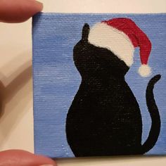 a painting of a black cat with a santa hat on it's head is shown