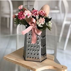 a vase filled with pink and white flowers on top of a wooden table next to a chair