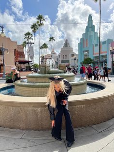 a woman is posing in front of a fountain