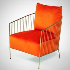 an orange chair sitting on top of a white floor next to a red pillow in front of it