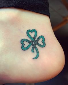 a tattoo on the foot of a person with four - leaf clovers in it