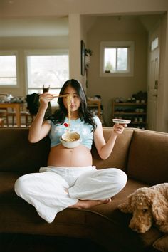 a pregnant woman eating food while sitting on a couch