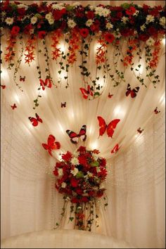 a vase filled with flowers and butterflies on top of a table next to a curtain