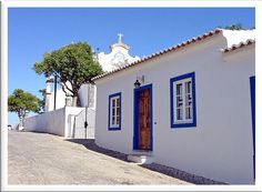 a white building with blue trim and windows on the street next to a church steeple