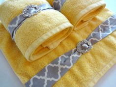 two yellow towels with grey and white designs on them, one is rolled up to the side