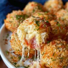 a white plate topped with cheesy meatballs covered in cheese and parmesan