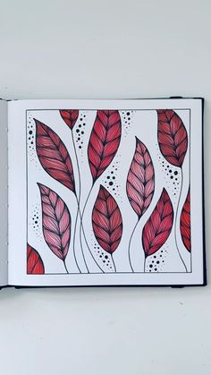 an open book with red leaves and dots on the cover, in front of a white wall