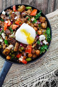 a skillet filled with meat, vegetables and an egg