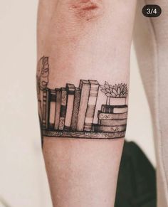 a person with a tattoo on their arm that has books and plants on it,