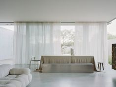 a living room filled with white furniture and curtains on the windows sill above it