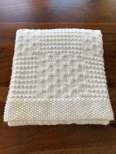 a white knitted blanket sitting on top of a wooden floor