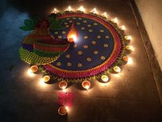 a lit diya on the ground with candles around it and some lights in the middle