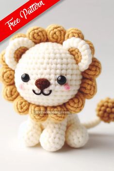 a crocheted lion sitting on top of a white table next to a red ribbon