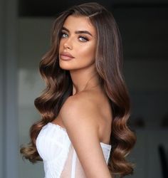 a woman with long brown hair is wearing a white dress and posing for the camera