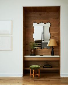 a mirror sitting on top of a wooden shelf next to a table with a stool