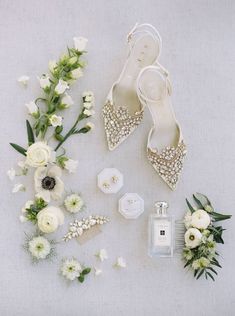 wedding shoes and bouquets laid out on the floor next to each other, including perfume bottle