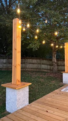 an outdoor patio with lights strung from the ceiling and wooden pillars on top of it