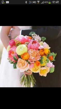 a bride and groom holding a bouquet of colorful flowers in their hands at the end of their wedding day