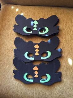 three pieces of paper cut out to look like cats with green eyes and black ears