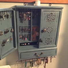 a blue cabinet with earrings hanging from it's sides